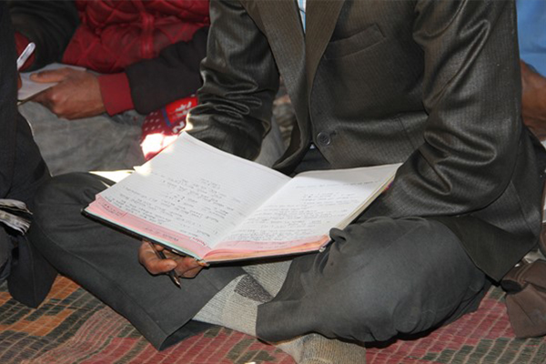 Bible in lap of man sat on floor
